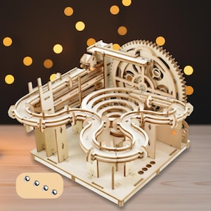 May include: A wooden marble run kit with a complex design featuring ramps, loops, and a large gear. The natural wood color contrasts with the silver marbles. The kit is designed for assembly and play.