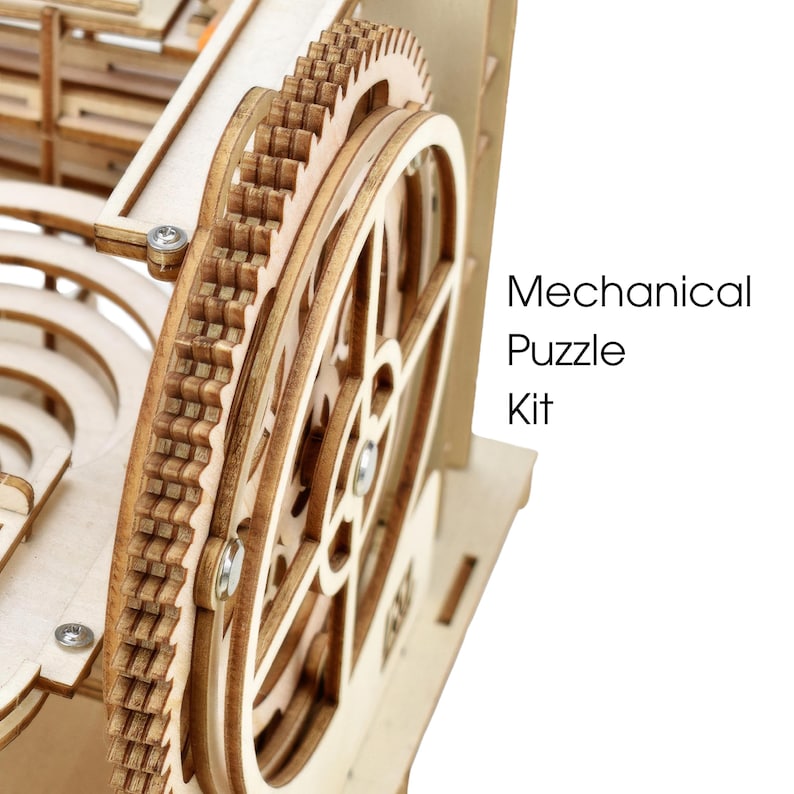 May include: Close-up of a wooden mechanical puzzle kit. The image shows intricate gears and a wheel, all made of light-colored wood. The text "Mechanical Puzzle Kit" is visible on the right side of the image.