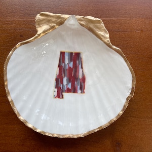 May include: A white seashell dish with a gold rim. The dish has a colorful image of the state of Alabama inside.