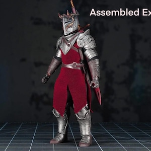 May include: A detailed action figure of a knight in full armor. The figure is clad in silver-colored metal armor with a red tunic and cape. The helmet has a crown, and the figure is holding a sword. The text "Assembled Example" is in the upper right.