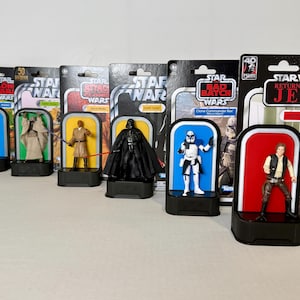 May include: A collection of Star Wars action figures in their original packaging. The figures include Darth Vader, Clone Commander Rex, Han Solo, and more. The packaging is vintage-inspired and features the Star Wars logo.