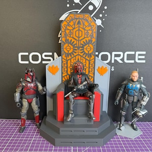 以下が含まれることがあります： SFアクションフィギュア3体。1体はオレンジとグレーのデザインの玉座に座っています。他の2体は立っており、1体は赤とグレーの鎧、もう1体は黒と青の鎧を着ています。