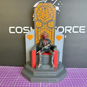 May include: A detailed action figure of Darth Maul seated on a throne. The throne is gray, red, and orange with intricate geometric designs. The figure is holding a lightsaber. The background features the text "COSMOS FORCE".