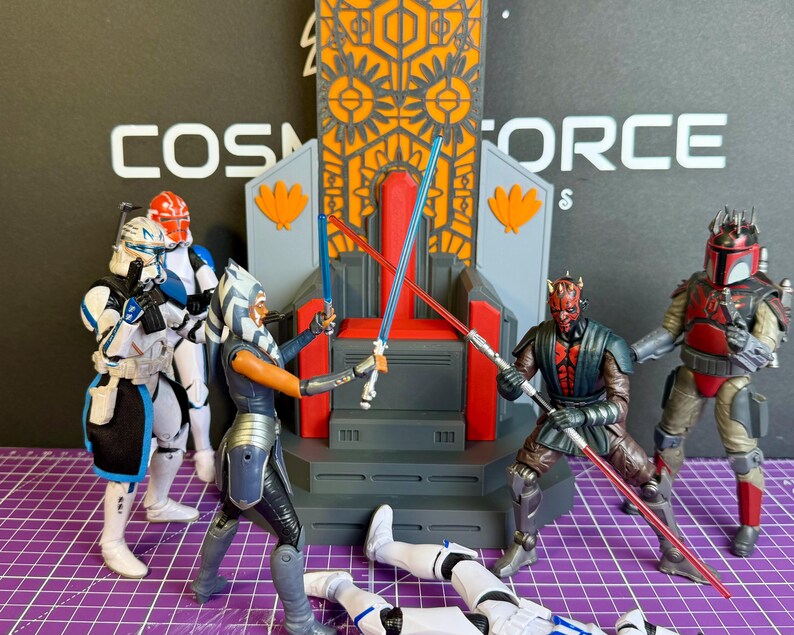 May include: Action figures of Star Wars characters in a battle scene. Ahsoka Tano and Darth Maul are engaged in a lightsaber duel, with other figures and a throne in the background. The word "Cosmoforce" is visible.