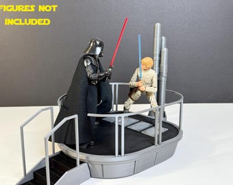Puede incluir: Una plataforma gris con una barandilla y escaleras. La plataforma tiene una superficie negra y está diseñada para parecerse a una estación espacial de Star Wars. El texto "FIGURES NOT INCLUDED" es visible en el fondo.