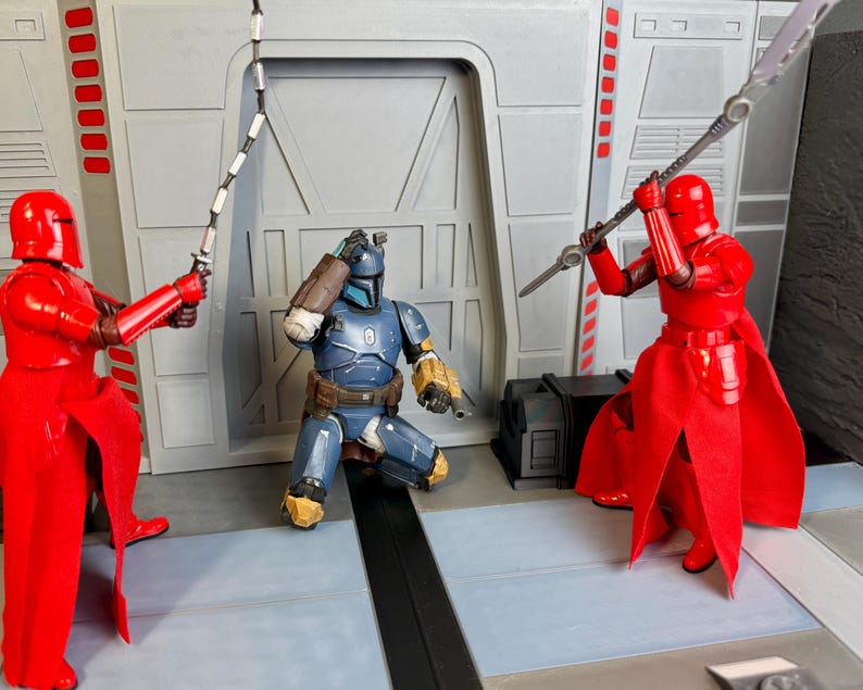 Puede incluir: Escena con figuras de acci&oacute;n en un entorno de ciencia ficci&oacute;n. Dos figuras con armadura roja se enfrentan a una figura con armadura azul. Una figura roja empu&ntilde;a una espada, la otra una lanza. La figura azul est&aacute; arrodillada, aparentemente angustiada.