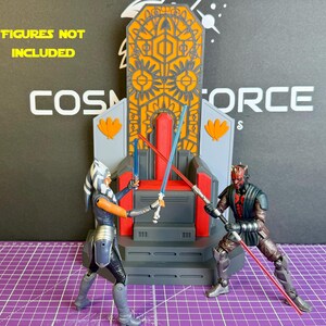 May include: A detailed diorama featuring a throne with intricate orange and gray designs. Two action figures, one with blue lightsabers and the other with red, are posed in a battle scene. The text "FIGURES NOT INCLUDED" is visible.