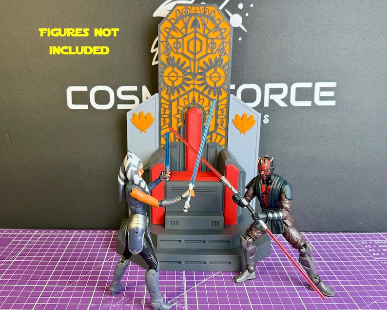 May include: A detailed diorama featuring a throne with intricate orange and gray designs. Two action figures, one with blue lightsabers and the other with red, are posed in a battle scene. The text "FIGURES NOT INCLUDED" is visible.