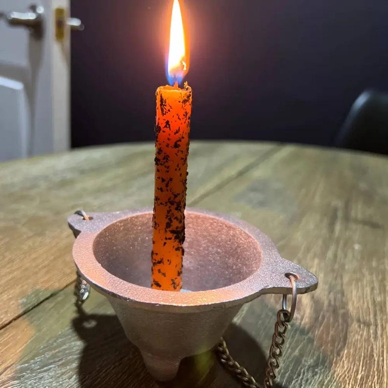 Medusa ritual terracotta candle holder with lit orange candle and chains
