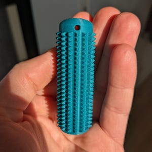 Peut inclure: Un cylindre texturé bleu turquoise avec un petit trou en haut. Le cylindre a un motif strié.