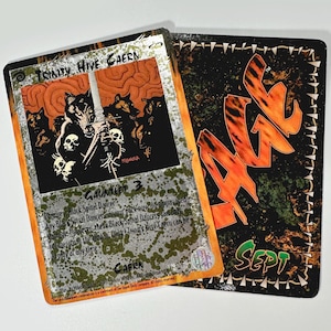May include: A black and white trading card with a silver foil border. The card features a black and white illustration of a wolf-like creature holding a sword. The card text reads "Trinity Hive Caern, Gauntlet 3, Pamires Black Spiral Dancer, Any Black Spiral Dancer summon Pack Wolves, If there is a Black Spiral Dancer summoned,  ignore the "Must Block" ability,  Only Trinity Hive Caern can be played at any time, Caern".