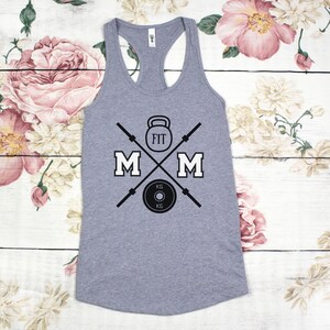 May include: Gray tank top with a black graphic design of a weightlifting barbell, kettlebell, and weight plate with the text "FIT MOM" in black.