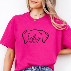T-Shirt featuring a minimalist design with dog ears and the phrase 'dog MOM' in cursive, perfect for dog lovers who want to showcase their love for their pets in a stylish and comfortable way.