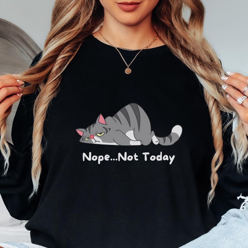 May include: A sweatshirt with a cartoon gray cat lying down with the text 'Nope...Not Today' printed below the cat.