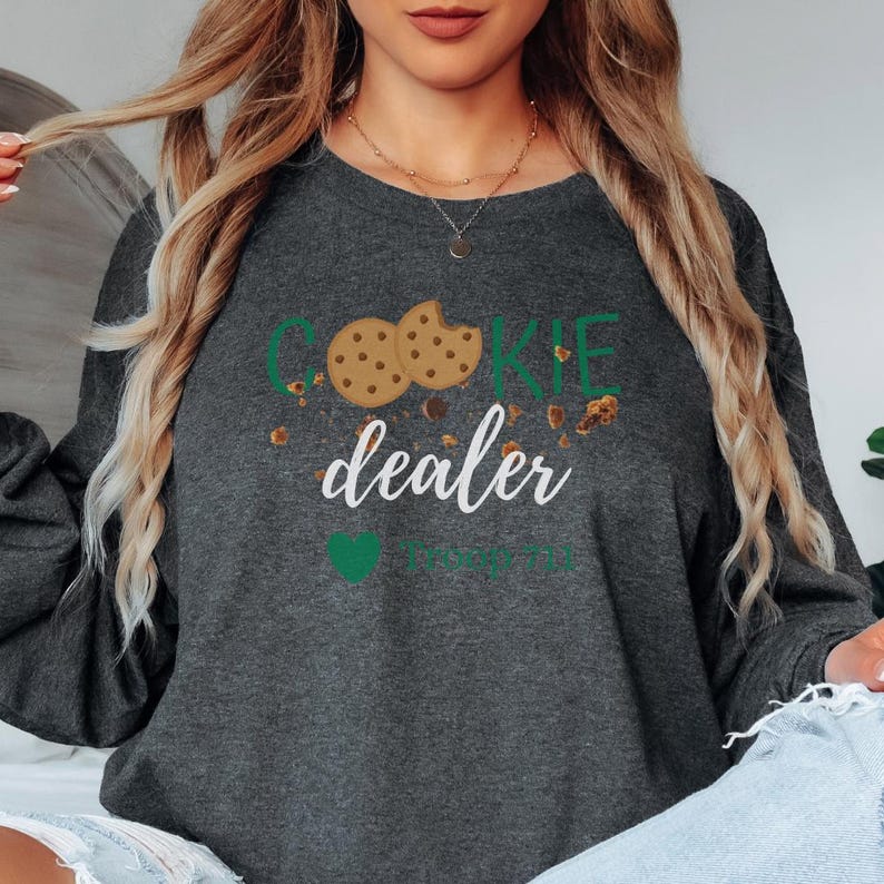Scout cookie dealer sweatshirt with playful cookie theme and troop number option. Cozy crewneck ideal for cookie season outfits, troop meetings, and scout mom gifts.