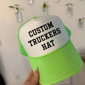 May include: A white and lime green trucker hat with the text "CUSTOM TRUCKERS HAT" in black lettering.