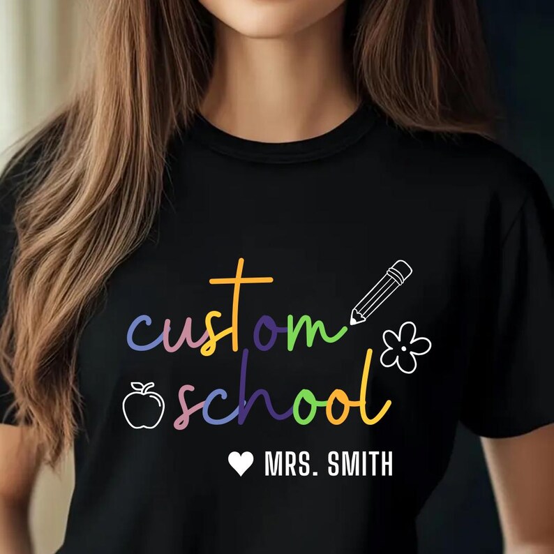 Cozy teacher crewneck sweatshirt customizable with school name and teacher’s name, featuring rainbow text and fun icons. A stylish and practical apparel piece for educators, making it a perfect gift for back-to-school, teacher appreciation, or everyday wear.