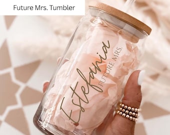 May include: A clear glass tumbler with a bamboo lid and a straw. The tumbler is personalized with the name "Estefania" and the text "FUTURE MRS." in a script font. The tumbler is filled with pink tissue paper.
