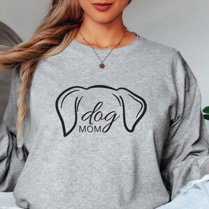 Sweatshirt featuring a minimalist design with dog ears and the phrase 'dog MOM' in cursive, perfect for dog lovers who want to showcase their love for their pets in a stylish and comfortable way.