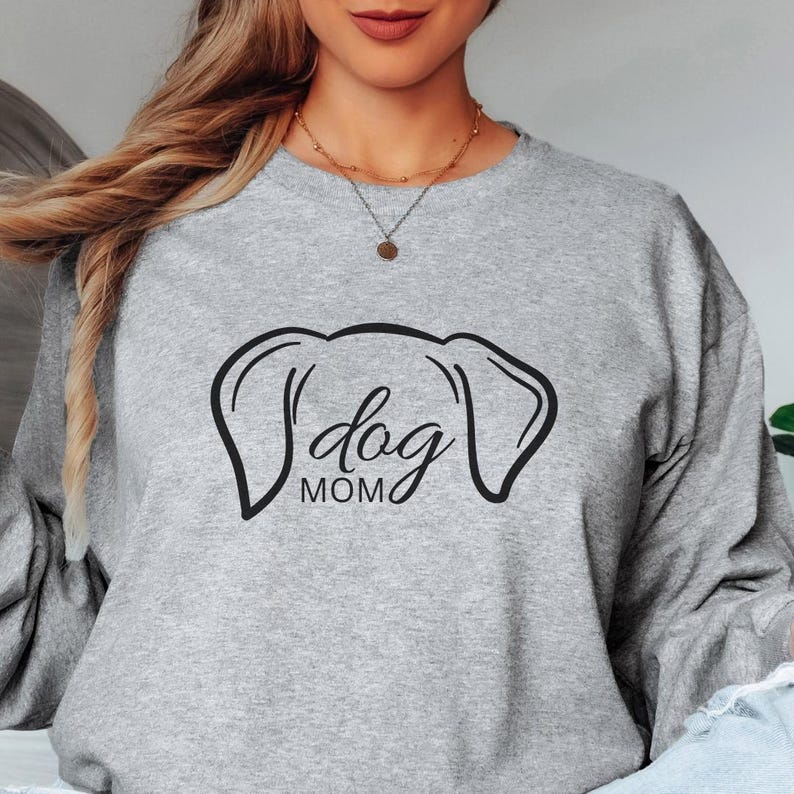 Sweatshirt featuring a minimalist design with dog ears and the phrase 'dog MOM' in cursive, perfect for dog lovers who want to showcase their love for their pets in a stylish and comfortable way.