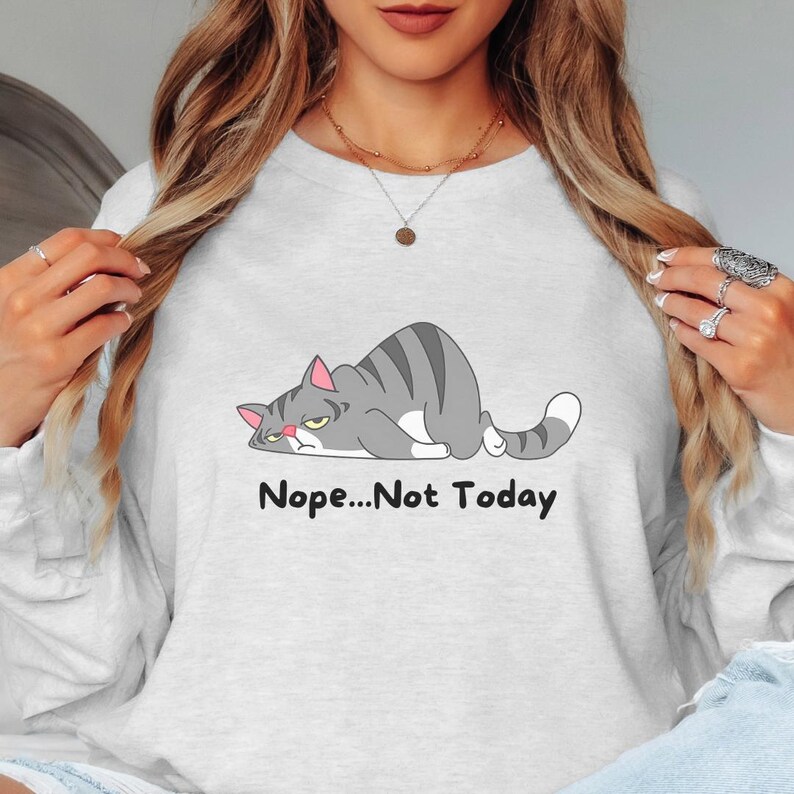 Cute lazy cat graphic sweatshirt with humorous text, shown in a relaxed unisex fit perfect for lounging, casual wear, or gifting to cat moms.