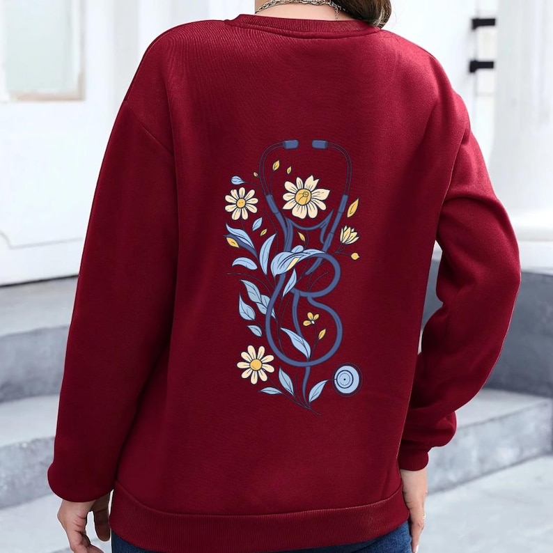 May include: A sweatshirt with a blue stethoscope and floral design on the back.