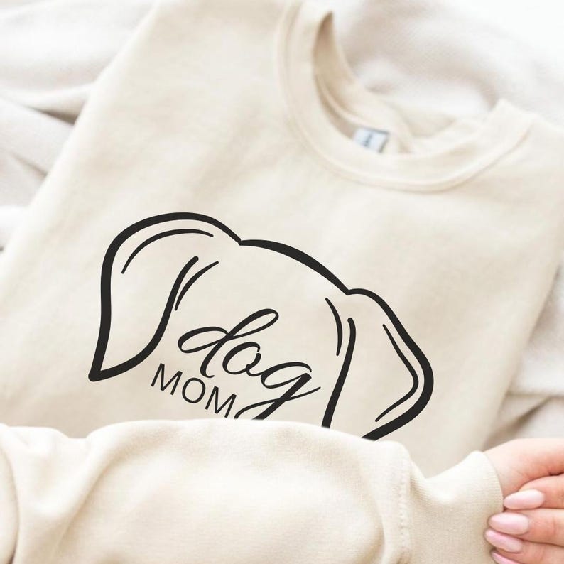 Sweatshirt featuring a minimalist design with dog ears and the phrase 'dog MOM' in cursive, perfect for dog lovers who want to showcase their love for their pets in a stylish and comfortable way.