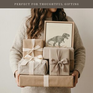 May include: A stack of wrapped gifts in various sizes and shades of brown, tied with cream-colored ribbons. A framed dinosaur drawing sits atop the gifts. The text "PERFECT FOR THOUGHTFUL GIFTING" is at the top of the image.