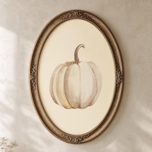 May include: An oval-shaped wall art piece featuring a watercolor illustration of a single pumpkin in shades of beige and cream. The artwork is encased in an ornate, antique-style bronze frame with intricate floral detailing along the edges.