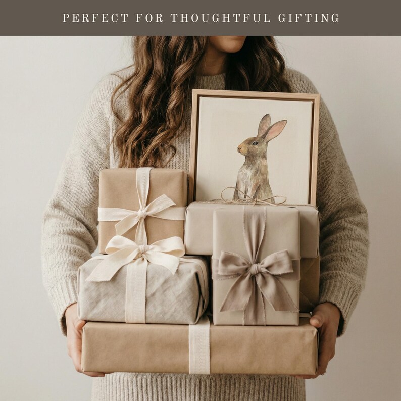 May include: A collection of rectangular gift boxes wrapped in plain brown paper, tied with cream and beige fabric ribbons. One box is topped with a framed illustration of a brown rabbit. The text "PERFECT FOR THOUGHTFUL GIFTING" is visible.