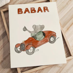 Puede incluir: Ilustración enmarcada de Babar, el elefante, conduciendo un coche rojo antiguo. La palabra "BABAR" está escrita en rojo encima de la imagen. Babar lleva una chaqueta verde y sostiene un sombrero.