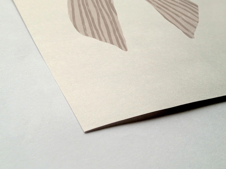 May include: Abstract art print featuring two beige shapes with vertical striped details on a cream-colored background. The artwork is presented on a textured paper, with a visible corner and a white surface.