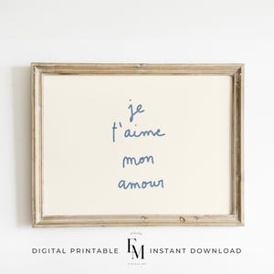 May include: A framed printable wall art print with a light beige background and blue handwritten text that reads "je t'aime mon amour".