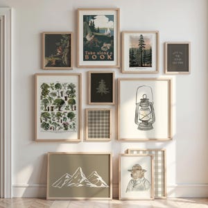 May include: A gallery wall of framed art prints with a nature theme. The prints depict trees, mountains, a lantern, and a bear in a ranger hat. The color scheme includes brown, green, and white, with a vintage aesthetic.