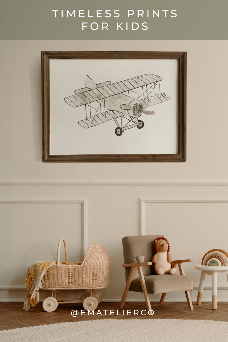 May include: A framed black and white illustration of a vintage airplane, hanging on a white wall with wainscoting. A wicker baby carriage and a plush toy are in the foreground. The text "TIMELESS PRINTS FOR KIDS" is at the top of the image. The text "@EMATELIERCO" is at the bottom of the image.