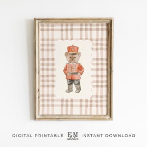 Könnte beinhalten: Gerahmter Digitaldruck mit einer Aquarellillustration eines Teddybären in roter Militäruniform und Hut. Der Hintergrund ist ein beige-weißes Karomuster. Der Rahmen ist hellbraun.