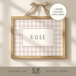 Peut inclure: Impression encadrée avec le nom "ROSE" en police serif, sur un motif vichy beige et blanc. Le cadre en bois est suspendu par un ruban beige noué en nœud. Plus de couleurs disponibles.