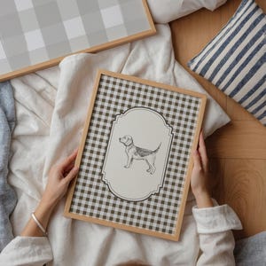 Pu&ograve; includere: Illustrazione incorniciata di un cane con sfondo a scacchi marrone e bianco. La cornice &egrave; marrone chiaro. &Egrave; visibile anche un secondo pezzo incorniciato con un motivo a scacchi grigio e bianco. Nell'immagine &egrave; presente anche un cuscino a righe blu e bianche.