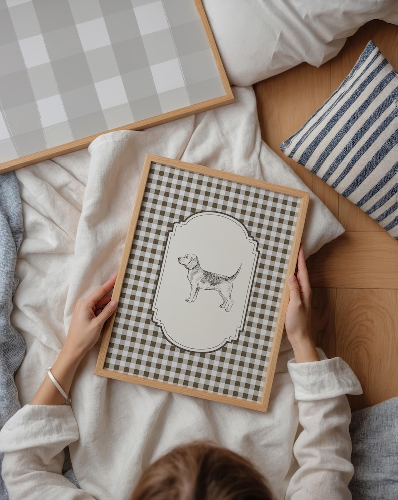 Pu&ograve; includere: Illustrazione incorniciata di un cane con sfondo a scacchi marrone e bianco. La cornice &egrave; marrone chiaro. &Egrave; visibile anche un secondo pezzo incorniciato con un motivo a scacchi grigio e bianco. Nell'immagine &egrave; presente anche un cuscino a righe blu e bianche.