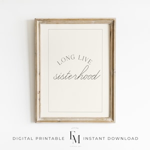 May include: A printable wall art print with a white background and black text that reads "Long Live Sisterhood". The print is framed in a light brown wood frame.