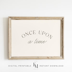 May include: A framed print featuring the phrase "ONCE UPON a time" in black script on a cream background. The print is enclosed in a light brown, rustic frame. The bottom of the frame includes the text "DIGITAL PRINTABLE" and "INSTANT DOWNLOAD".