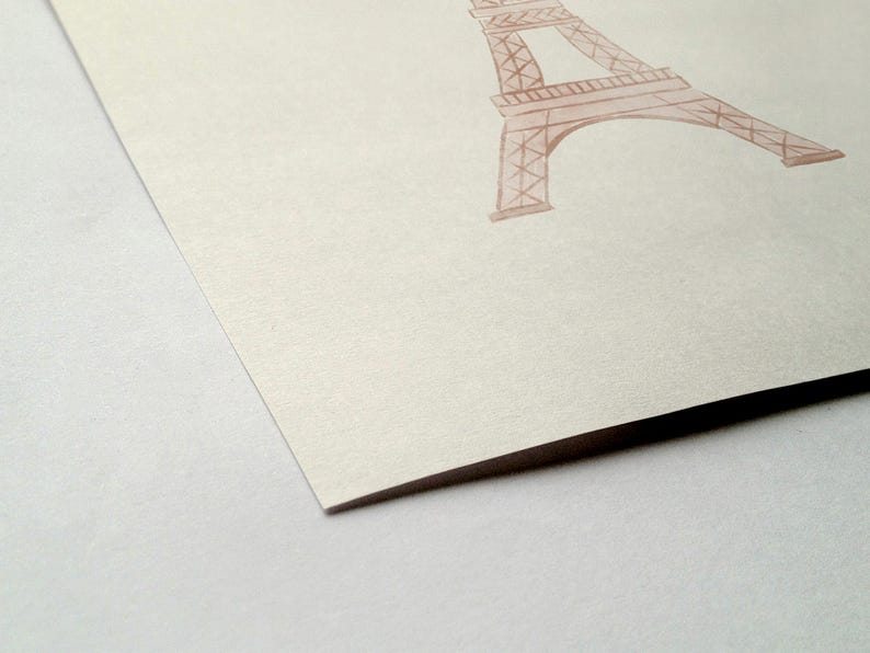 May include: A watercolor illustration of the Eiffel Tower in a soft, muted pink hue. The artwork is on a textured, off-white paper, with the tower's architectural details visible. The image is a close-up, focusing on the tower's structure.