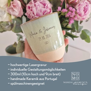 May include: A ceramic mug with a light green glazed upper section and a matte beige base. The mug features the laser-engraved text Maria & Johannes, the date 19.08.2016, and a small double ring icon. It has a 300ml capacity, 10cm height, and 9cm width.