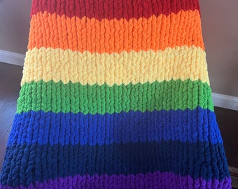 May include: A rainbow crocheted throw blanket with stripes of red, orange, yellow, green, blue, navy blue, and purple.