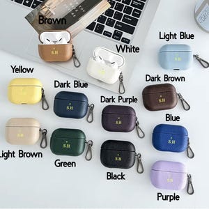 May include: Ten different colored leather cases for Apple AirPods with a gold S.H logo. The colors are yellow, brown, light brown, dark blue, green, black, white, light blue, dark brown, and purple.