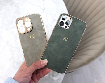 Op de afbeelding: Twee telefoonhoesjes, een grijs en een groen, met gouden accenten en de initialen "T.C." en "V.C." erop gedrukt.