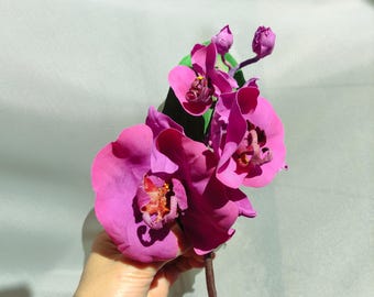 Peut inclure: Un bouquet d'orchidées roses avec des feuilles vertes. Les orchidées sont d'un rose foncé et sont disposées en grappe.