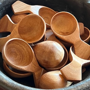 May include: A bowl filled with wooden scoops. The scoops are all made of light brown wood and have a rounded shape. They are perfect for serving small portions of food.