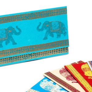 May include: A set of six colorful envelopes with gold trim and an elephant design. The envelopes are folded and stacked on a white surface.
