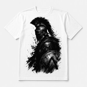 以下が含まれることがあります： 白いTシャツに、インクスタイルの黒と白のグラフィックが描かれています。横顔のスパルタ戦士が、とさか付きの兜をかぶり、中央に紋章が入った丸い盾を持っています。全体に芸術的な絵の具の飛び散りが施されています。